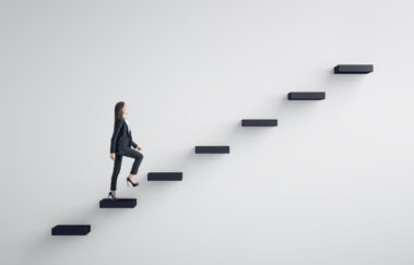 Side view of young businesswoman climbing stairs to success on concrete wall background. Leadership and career development concept
