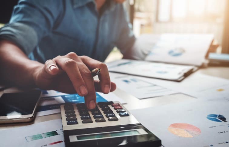 Man using calculator and charts to calculate part-time real estate agent salary