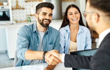 Real estate agent with couple shaking hands closing a deal and signing a contract