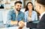 Real estate agent with couple shaking hands closing a deal and signing a contract