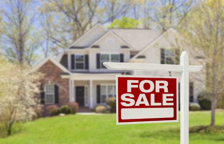 Suburban single-family home with a "For Sale" sign