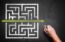 hand drawing a shortcut through a maze on a chalkboard