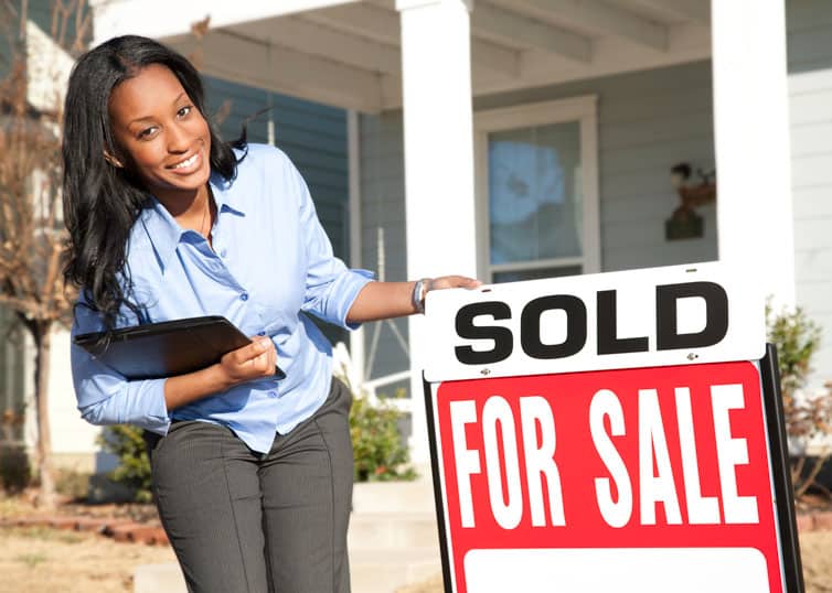 Top real esate agent putting up "Sold" sign in front of a single family house
