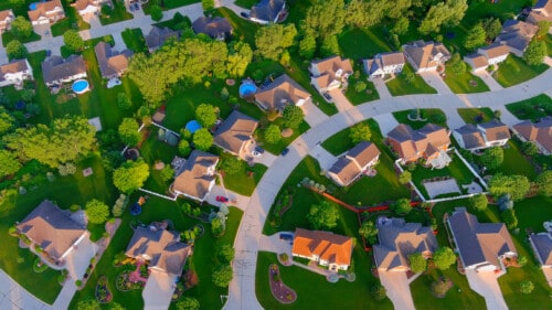 Curved street runs through idyllic summer neighborhood, early morning.