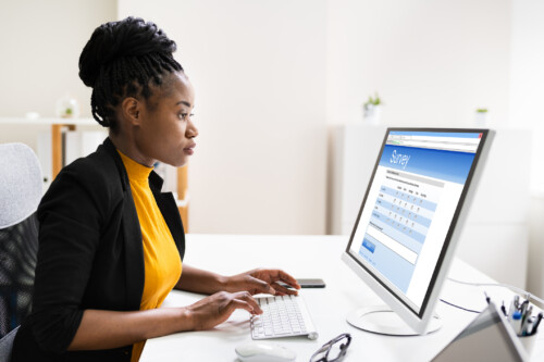 African Woman Filling Survey Poll Or Form On Desktop Computer