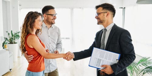Real estate agent shakes hands with new homeowners