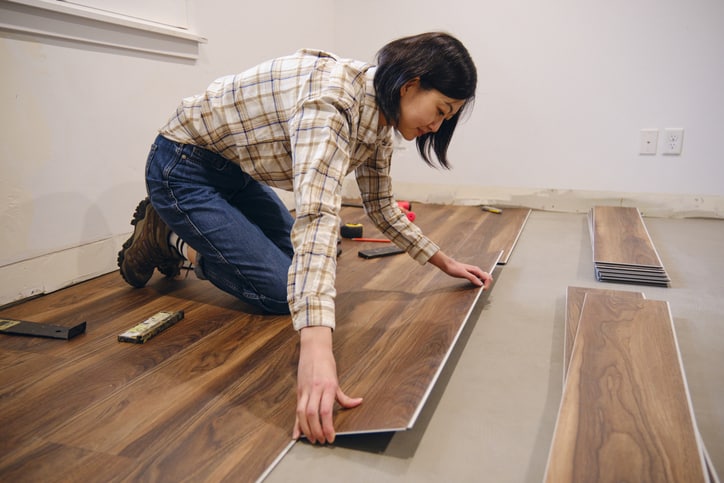 A woman installing laminate flooring in her home.