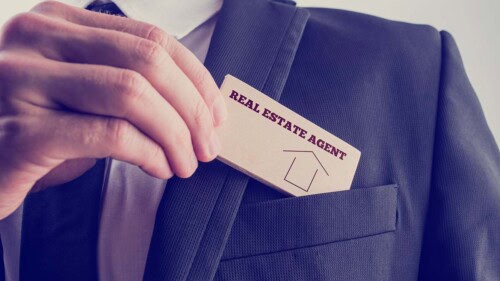 real estate agent puts business card in pocket