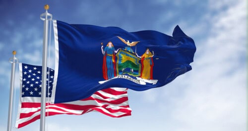 The New York state flag waving along with the national flag of the United States of America