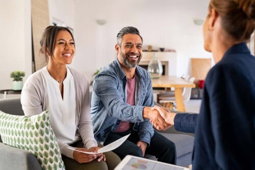 Couple shakes hands of real estate agent after discussion of types of property ownership.