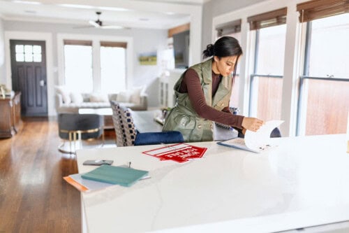 A real estate agent checks open house sign in sheets to plan follow up with potential buyers.
